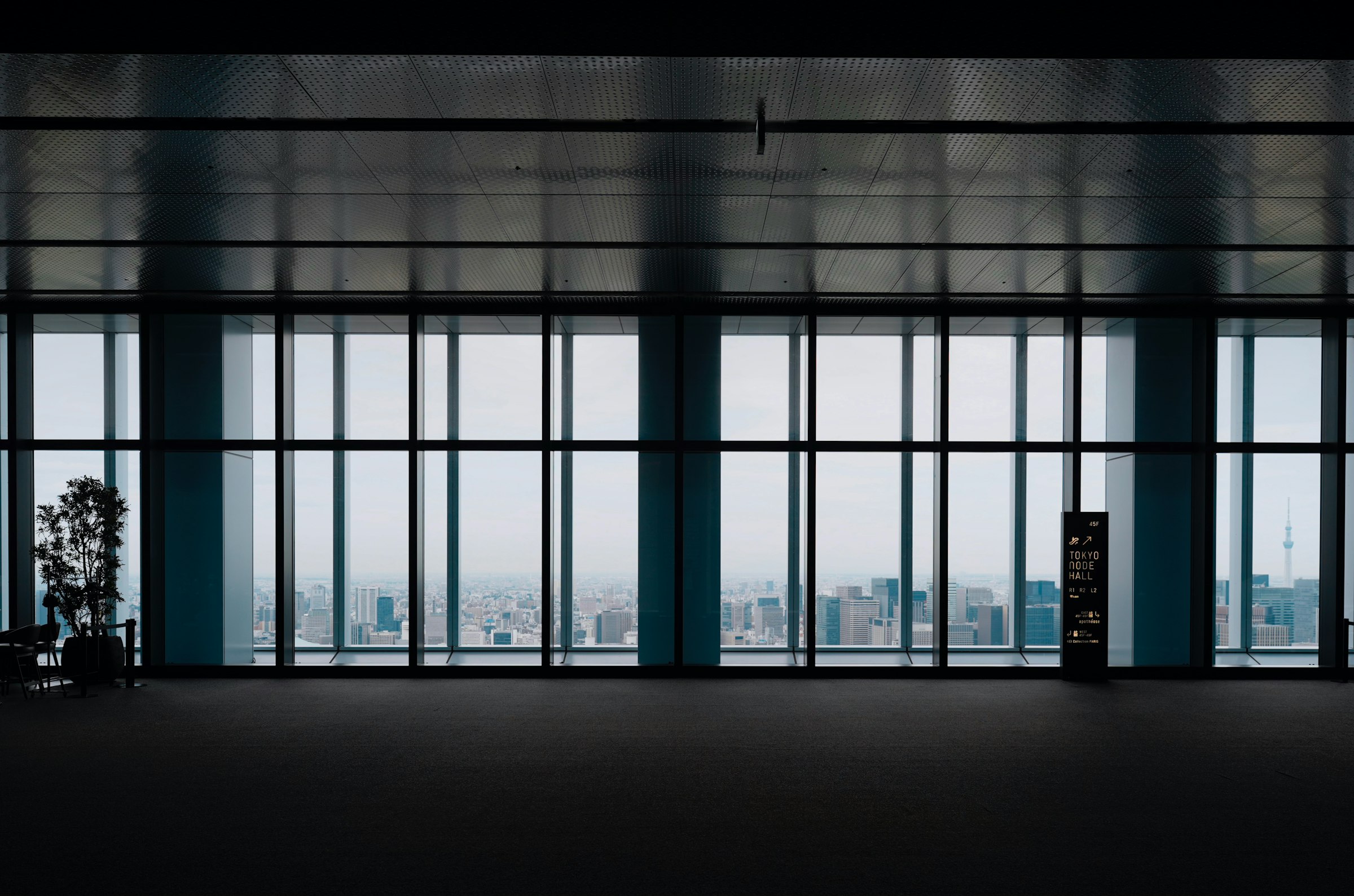 An empty modern workspace with floor-to-ceiling windows over a cityscape, where the work happens